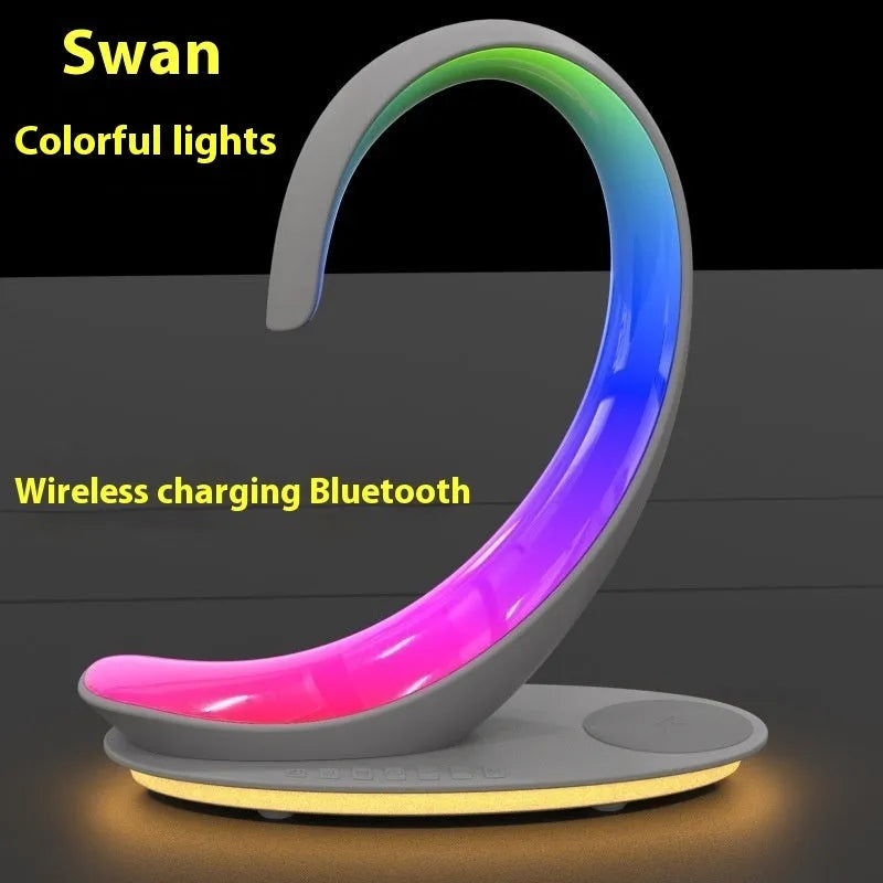 White swan-shaped desk lamp with wireless charging base and Bluetooth speaker emitting colourful light.
