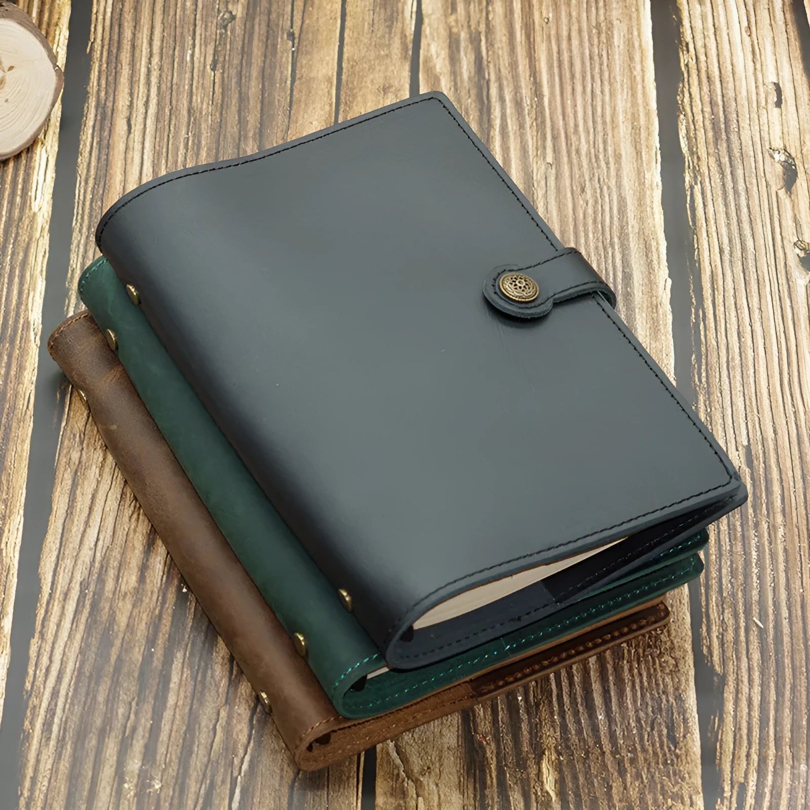 A5 handmade cowhide leather loose-leaf notebook in black with 100 sheets of kraft paper on a desk