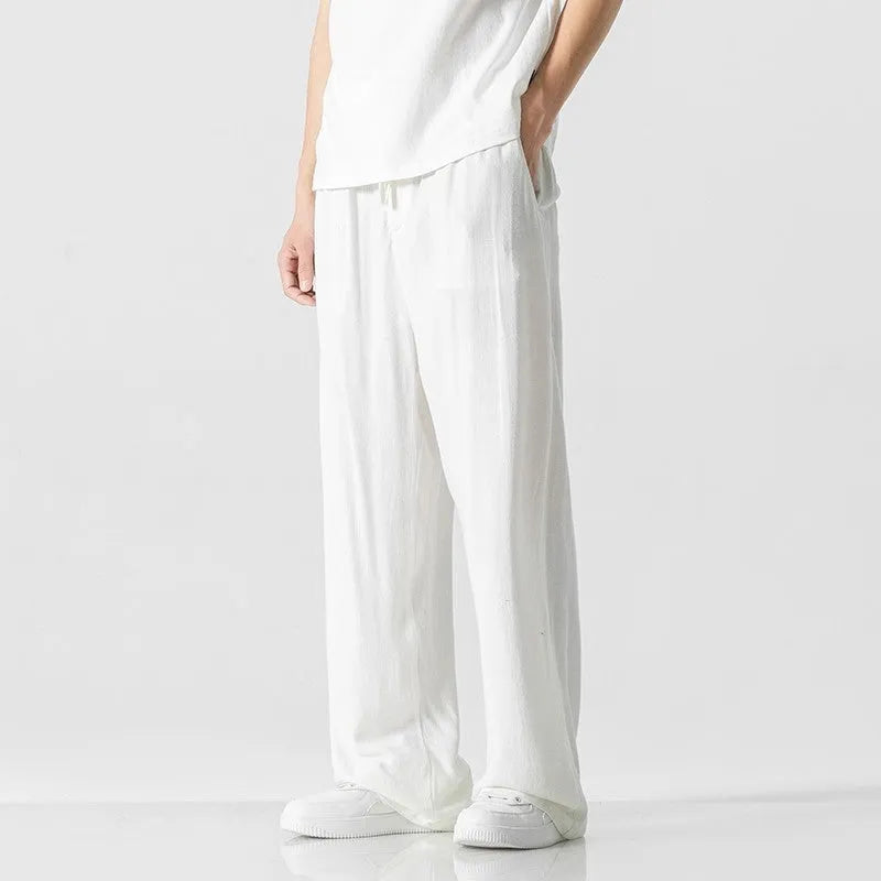 Men's beige loose-fit linen-style bamboo fibre trousers with a cropped leg and drawstring waist laid flat.