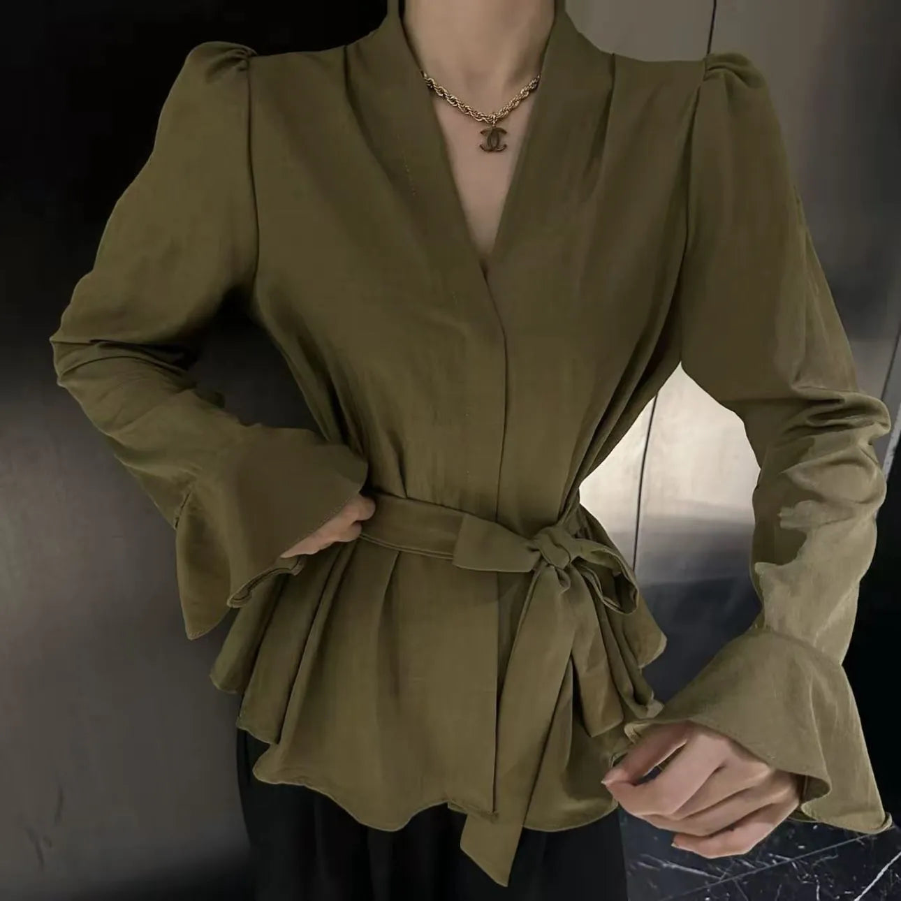 A woman's French-style black shirt with an irregular collar, long bell sleeves, and a tied front closure.