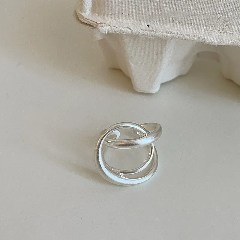 Geometric open ring with three-dimensional interlaced metal and matte electroplated finish in gold or silver colour