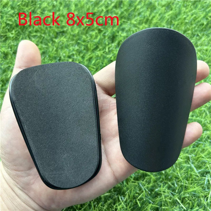 A pair of extra small mini plastic football shin guards, shown in either black or white.