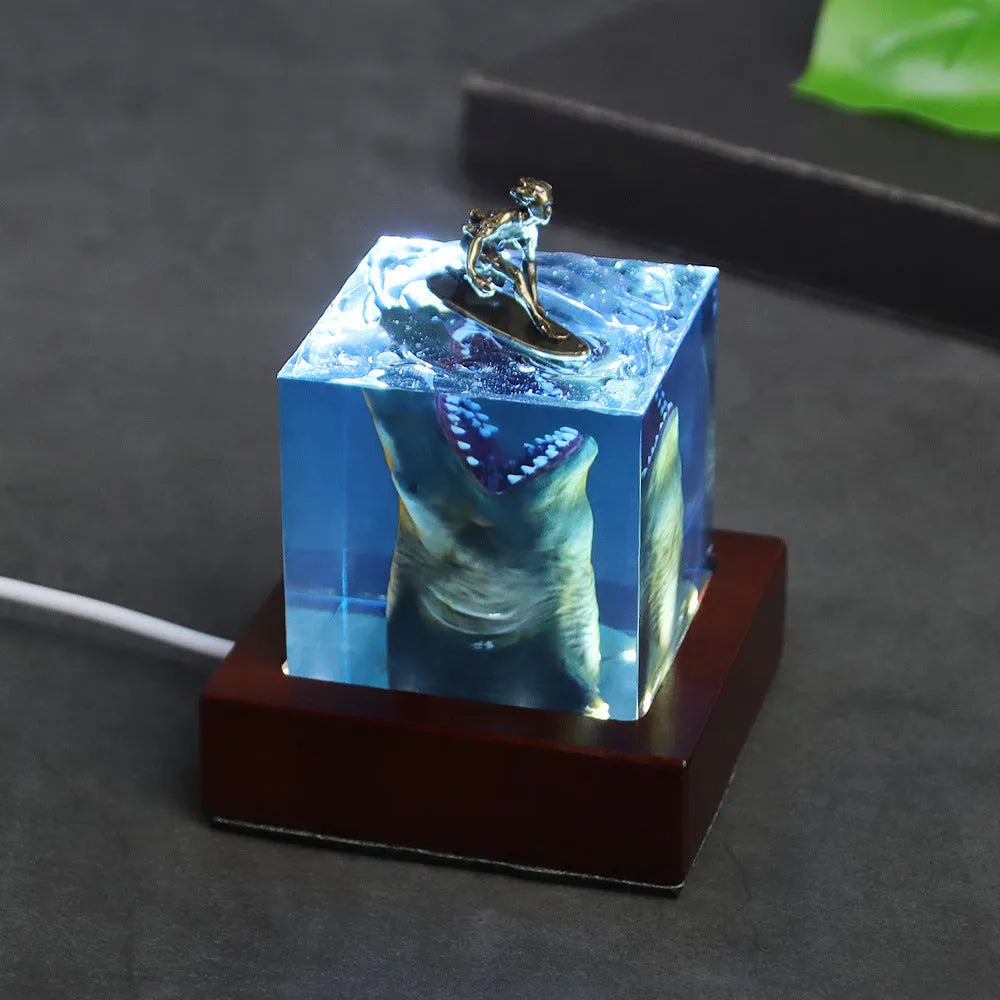 Clear epoxy resin ornament with shark surfing on a wave, includes lamp holder.