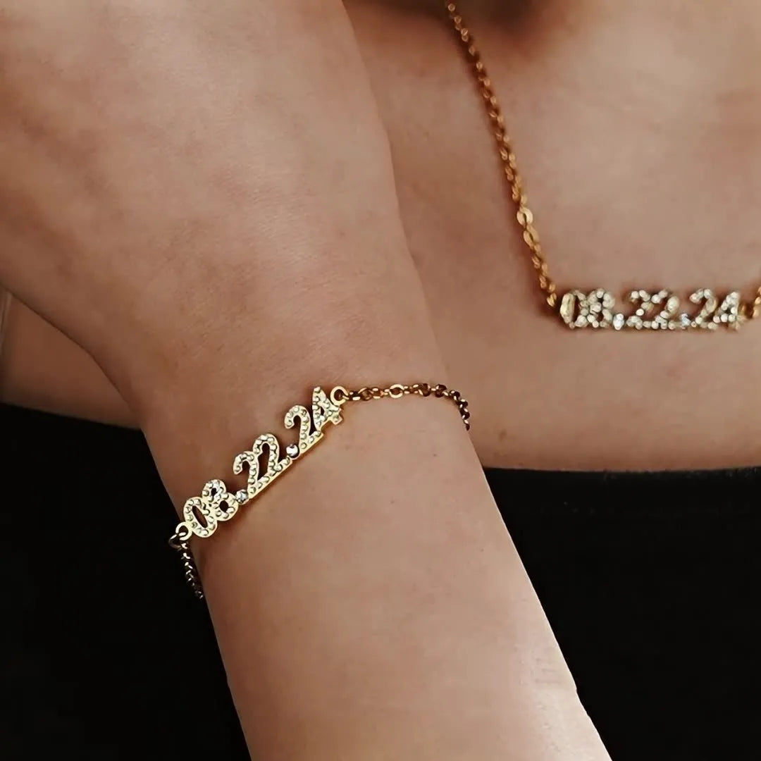 Stainless steel bracelet or necklace with diamond accents around digital numerals in gold, rose gold, or steel colour.