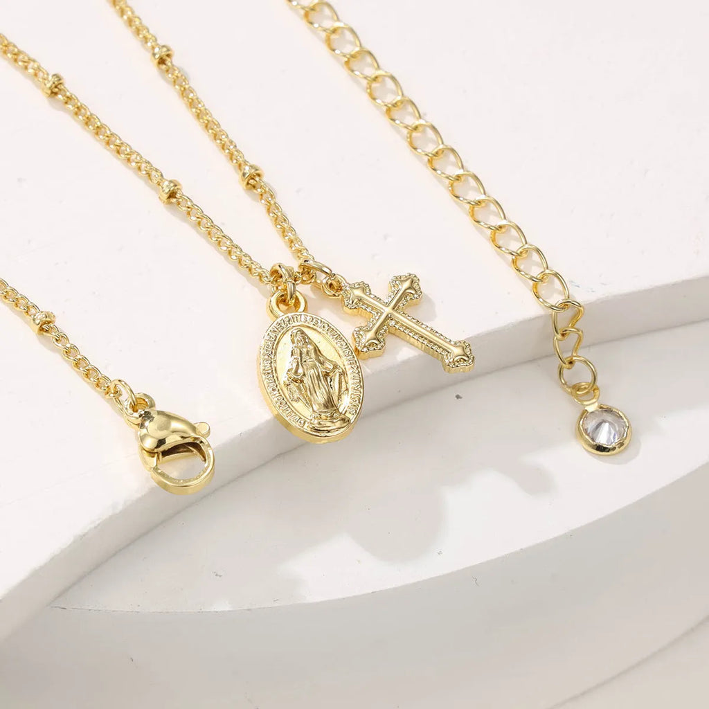 Gold-coloured geometric cross pendant necklace with a Virgin Mary ornament, on a chain.