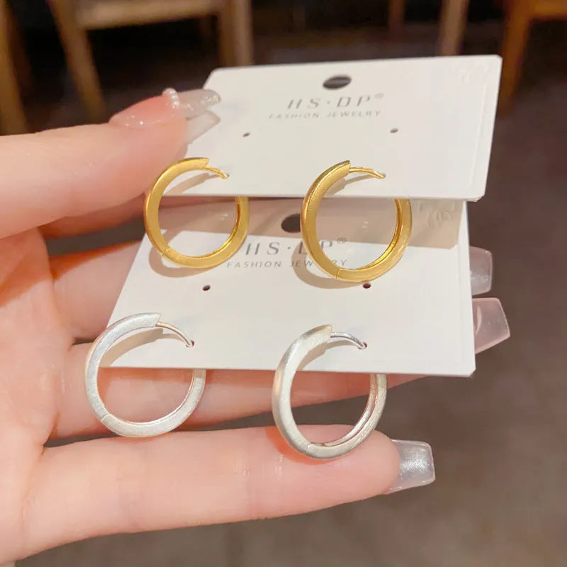 Gold and silver geometric round ear clip earrings for women on a simple background.