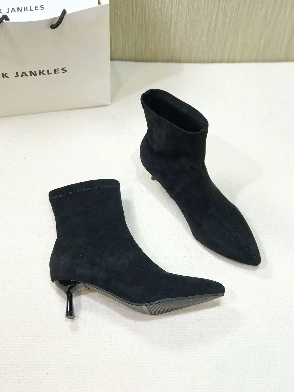 Black pointed toe ankle boots with high stiletto heel and mid-calf shaft showing microfiber texture