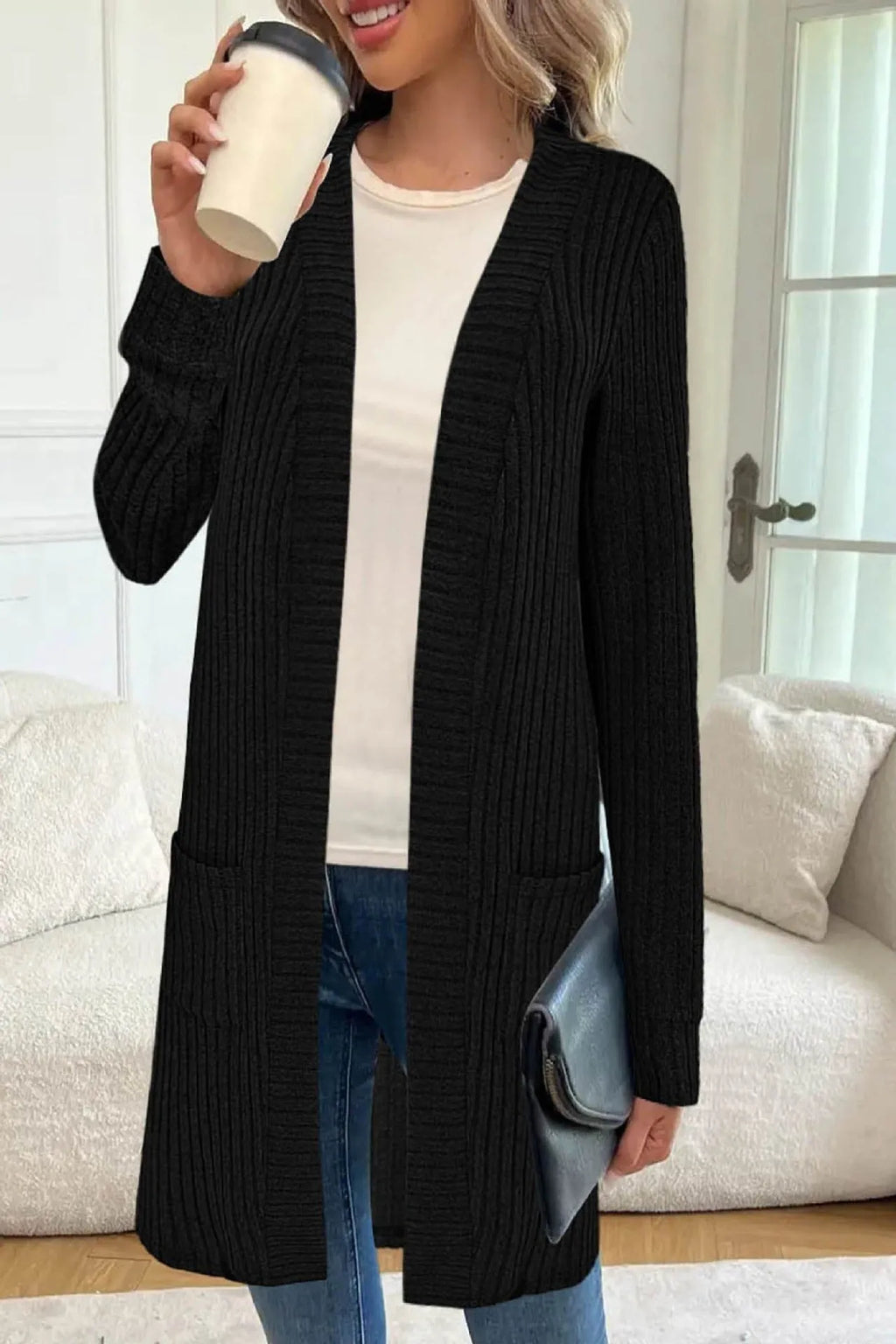 Woman wearing a loose fit, long sleeve, grey knitted cardigan jacket with patch pockets.