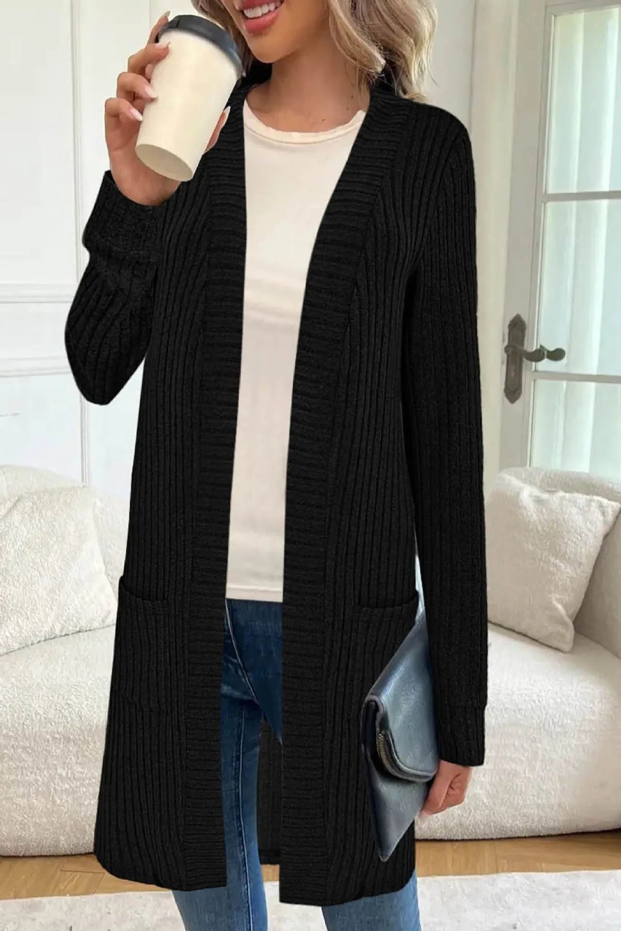 Woman wearing a loose fit, long sleeve, grey knitted cardigan jacket with patch pockets.
