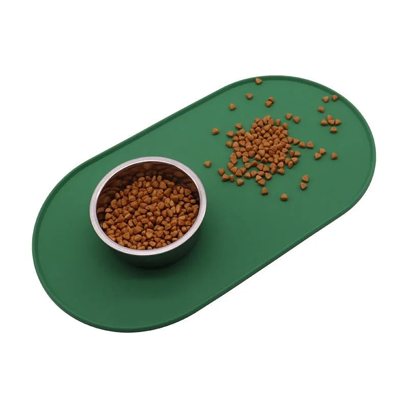 Green silicone cat feeding placemat with food and water bowls on a wooden floor