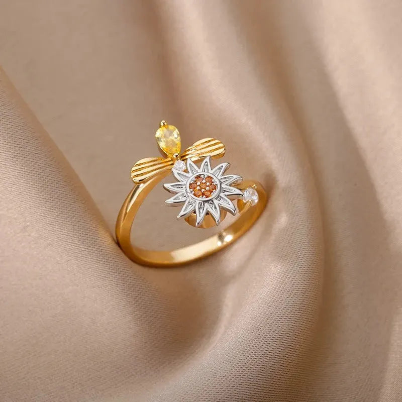 Gold and platinum coloured adjustable geometric decompression ring with rotatable element on a white background.