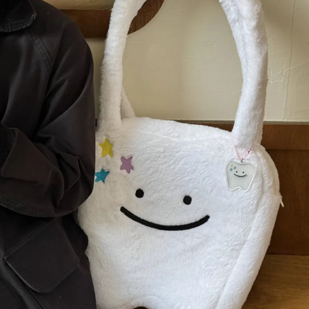 White plush tote bag with tooth decoration and shoulder strap showing zip opening