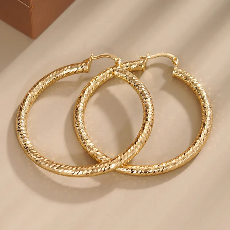 Close-up of women's geometric drop-shaped clip-on earrings with ring and line design in a copper and electroplated finish.