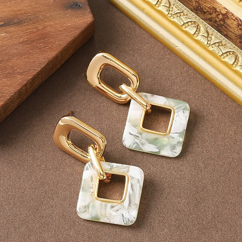 Pair of hollow geometric square copper earrings with chamfered corners in silver tone finish.