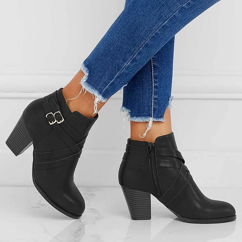 Grey PU leather short ankle boot with a 7cm chunky heel, side zip, and belt buckle on a wooden background.