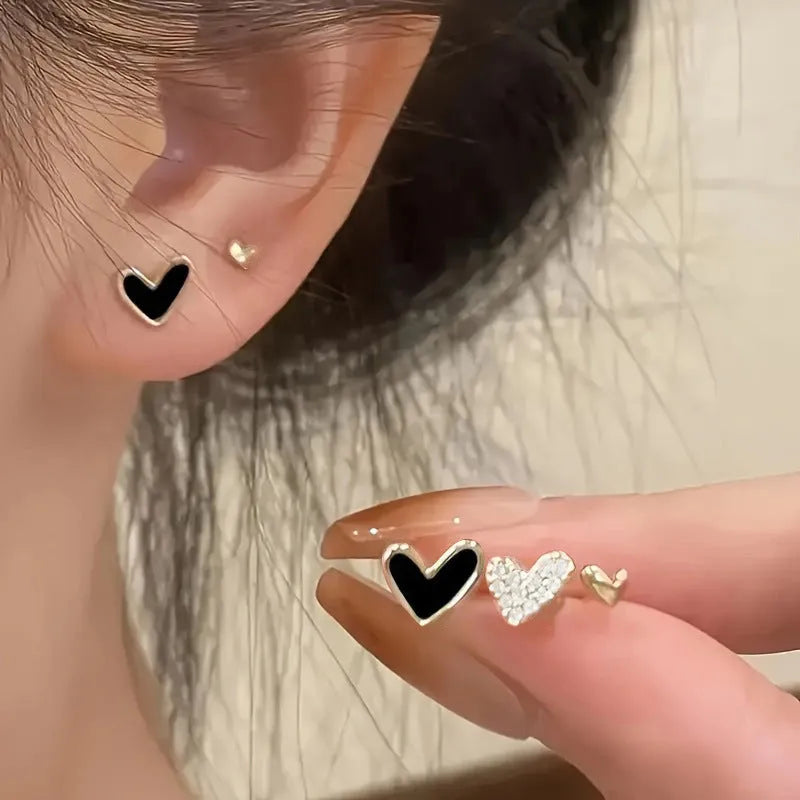 Three pairs of women's heart-shaped alloy earrings in gold, black, pink and black-white colours