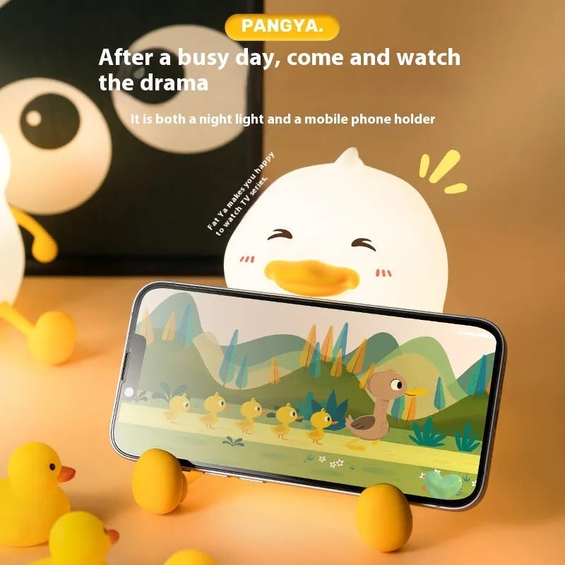 Chubby white USB rechargeable LED night light with built-in silicone phone holder on its base.