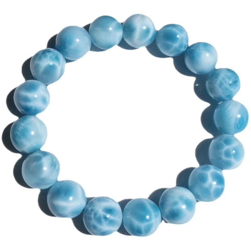 Blue handcrafted bodhi bracelet with sea-pattern crystal stones and pearl accents on a neutral background.