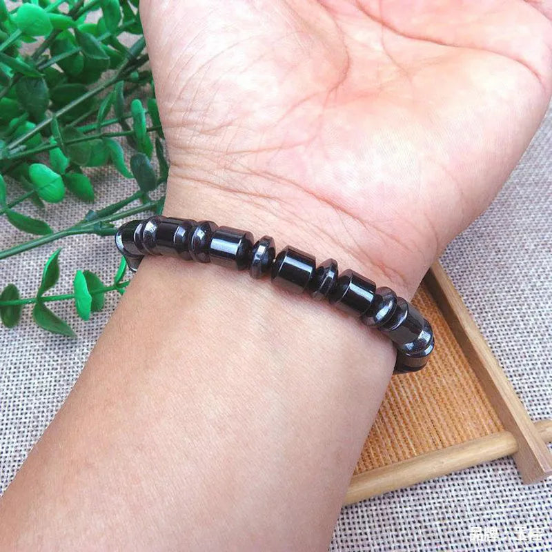 Black pentagram stone magnetic therapy bracelet with stretch fit on a wrist.