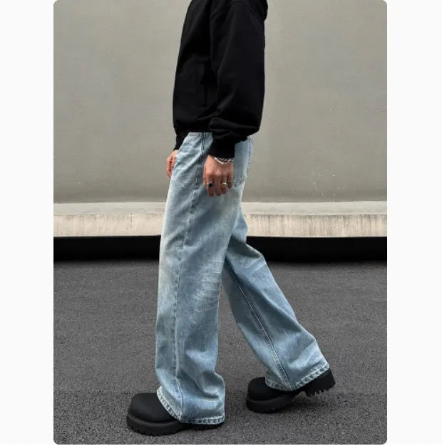 Men's blue straight-leg denim jeans with a whisker wash effect, showing a flared leg and visible stitching detail.
