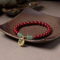 Handmade wave-shaped bracelet in cinnabar and copper beads on a wrist.