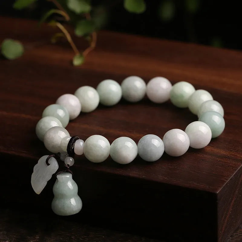 Natural green jade bracelet with a hanging Maitreya Buddha charm on a wrist.