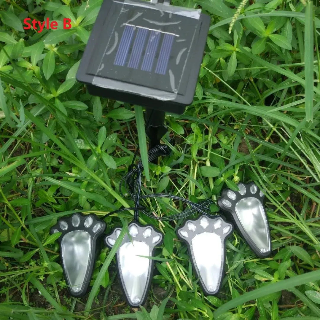 Set of four black solar-powered bear paw print LED garden lights with central solar panel pole.