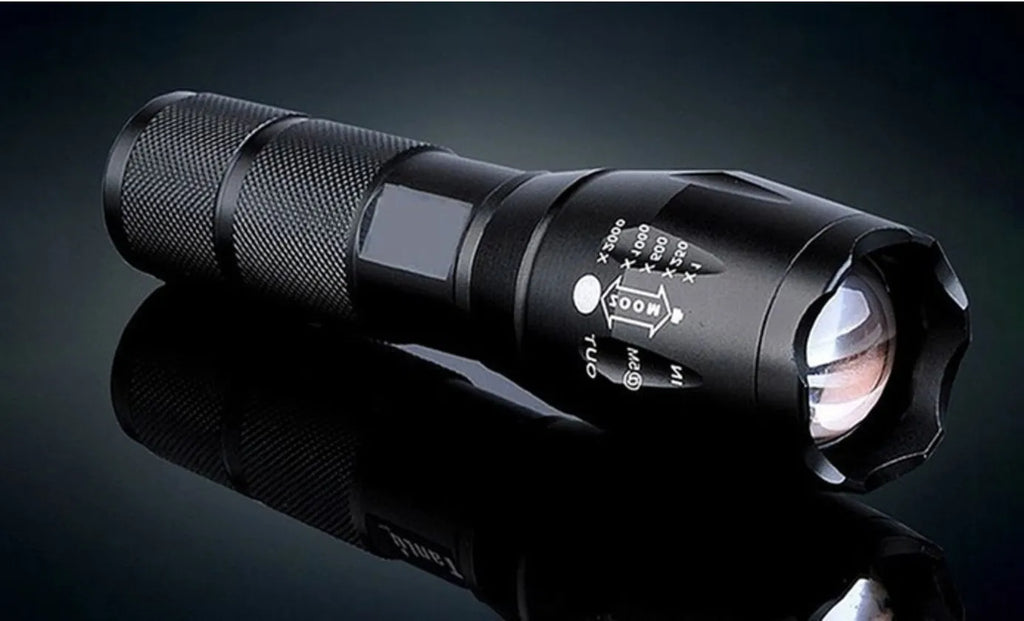 Black aluminium alloy LED zoom flashlight with adjustable focus head on a dark background.