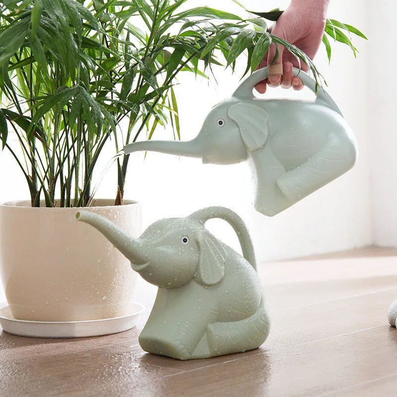 Blue elephant-shaped children's watering can with a long nozzle and baby bottle handle on a table.