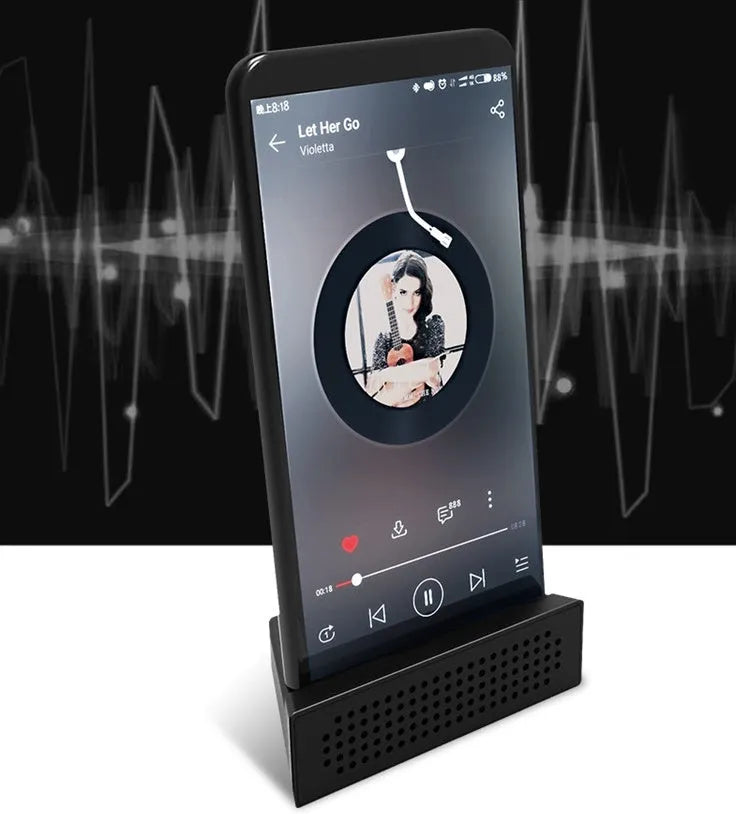 Mini black plastic phone amplifier bracket holding an Apple iPhone on a desktop