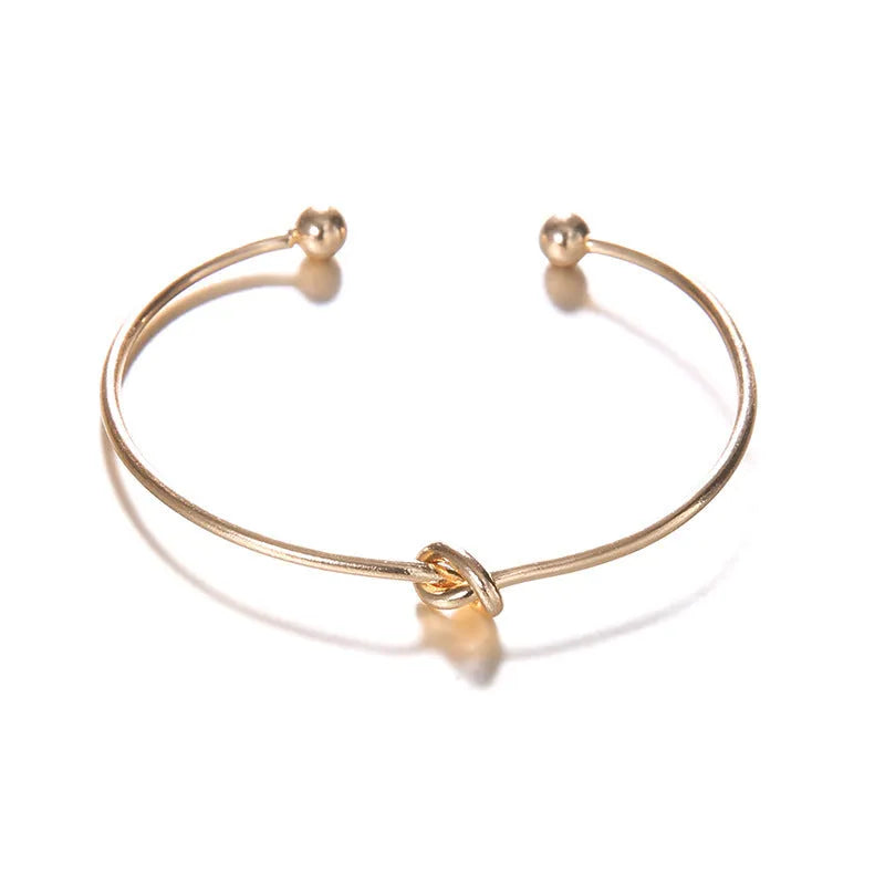 Gold electroplated alloy women's cuff bracelet with arrow and knotted design pattern