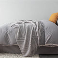 Small grey polyester blanket folded, dimensions 127 by 170 centimetres.