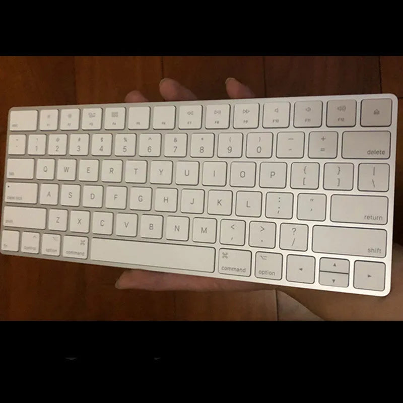 White Apple Bluetooth wireless keyboard with ultra-thin metal casing on a desk.