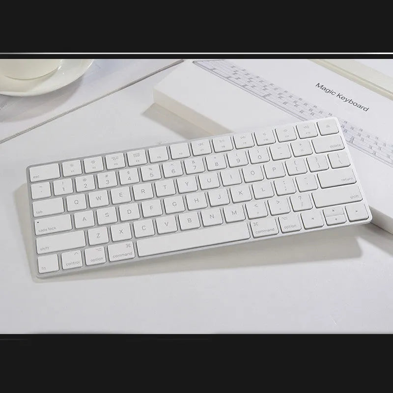 White Apple Bluetooth wireless keyboard with ultra-thin metal casing on a desk.