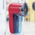 Portable electric lint remover handheld device on a blue background.