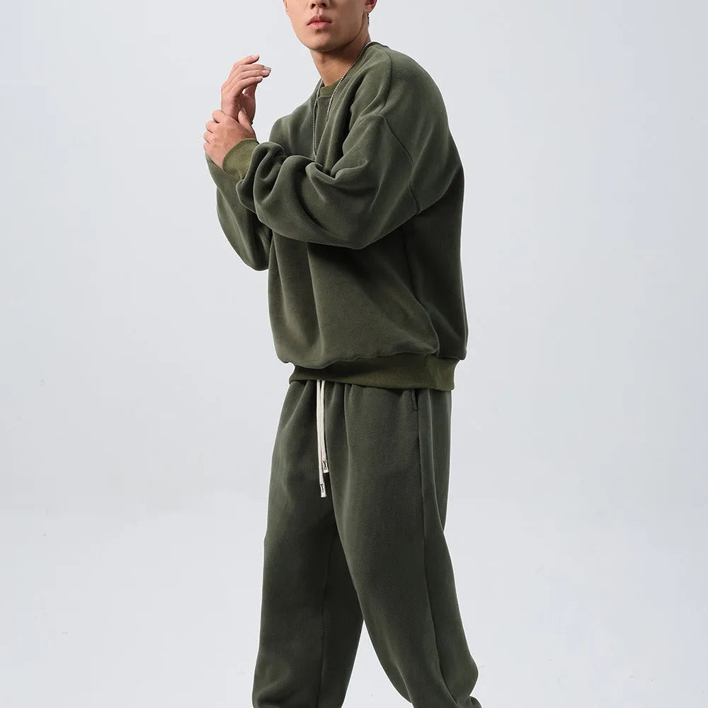 Man wearing a grey polar fleece crew neck coat and matching padded trousers from a casual winter sport suit set.