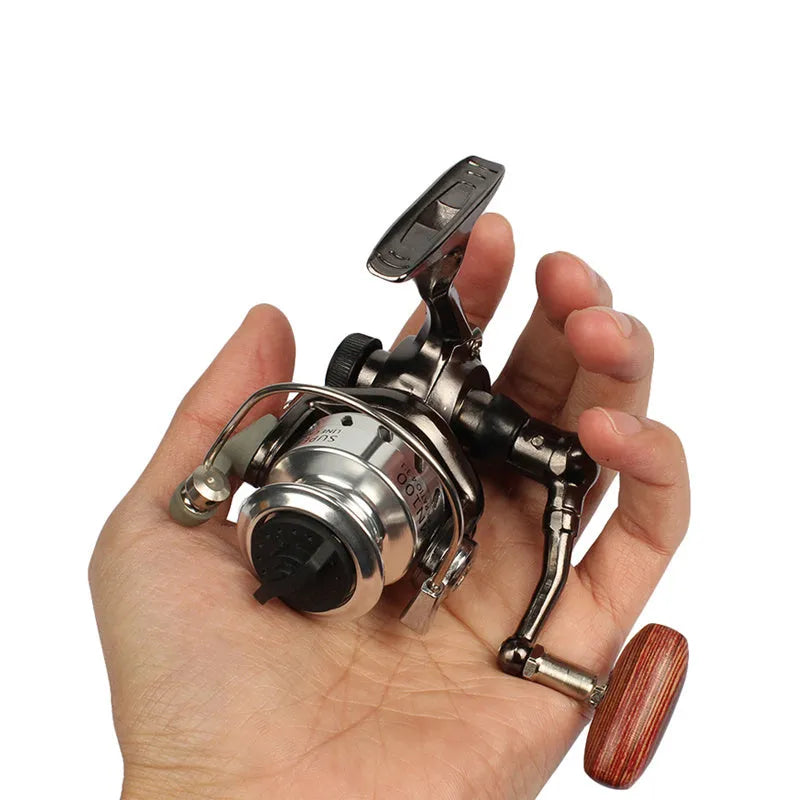 Mini 100 all metal black fishing reel with folding wooden rocker arm on white background