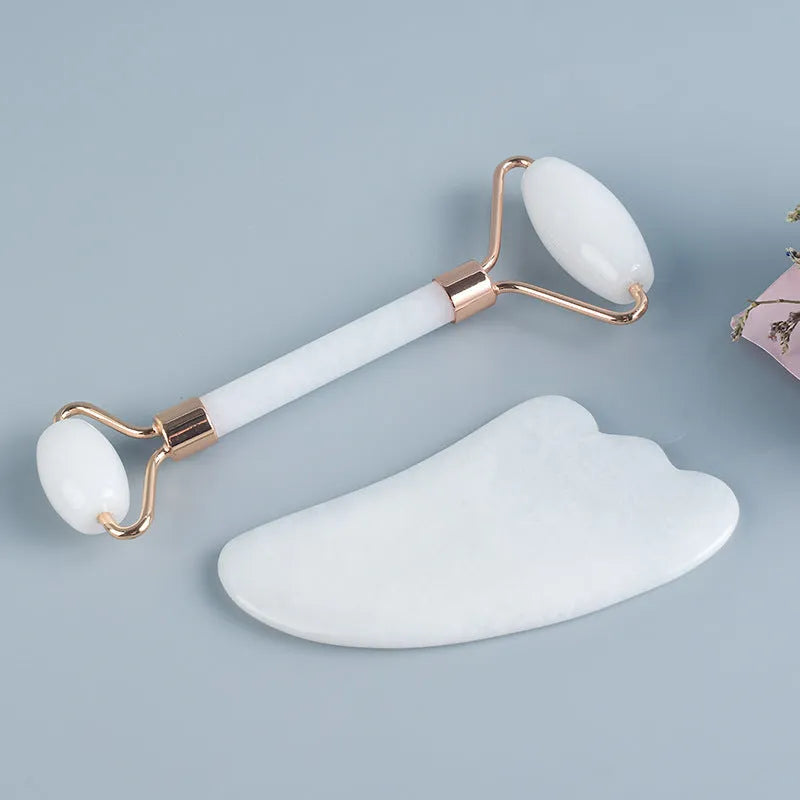 White jade facial roller and gua sha scraping tool set on a storage board.