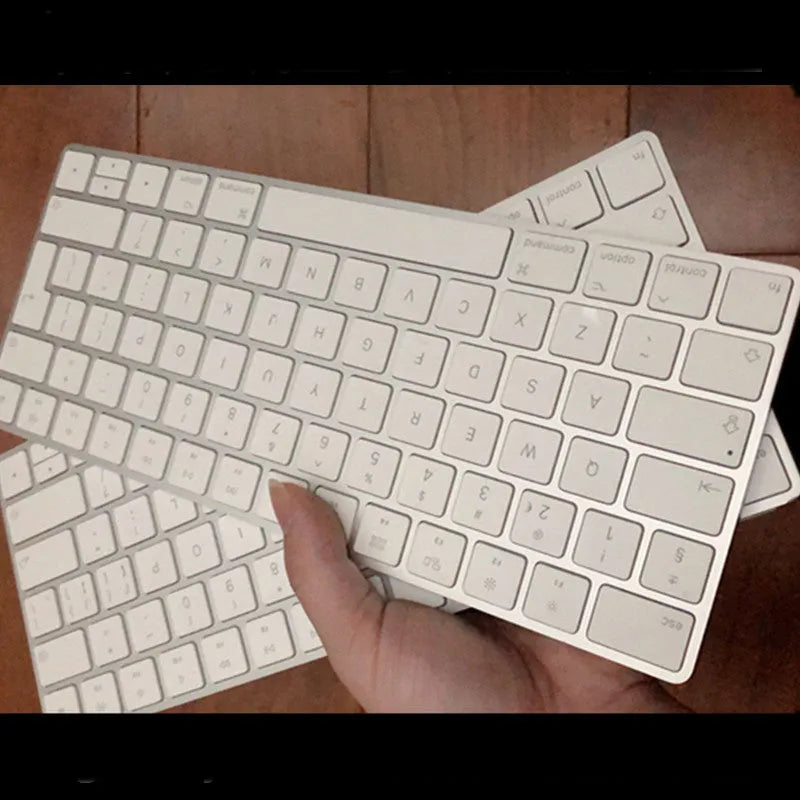White Apple Bluetooth wireless keyboard with ultra-thin metal casing on a desk.