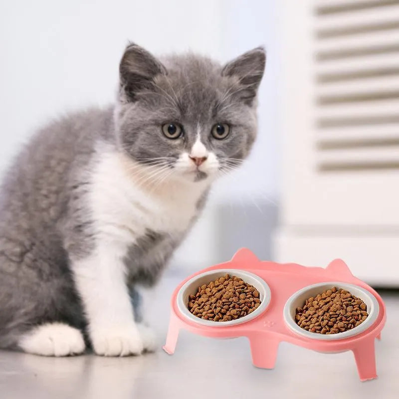 Blue ceramic cat food and water bowls on a white elevated stand with a storage hook.