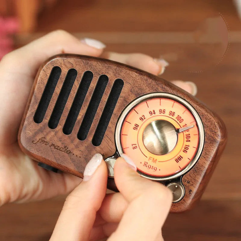 Retro wooden mini Bluetooth speaker in cherry wood finish on a table.