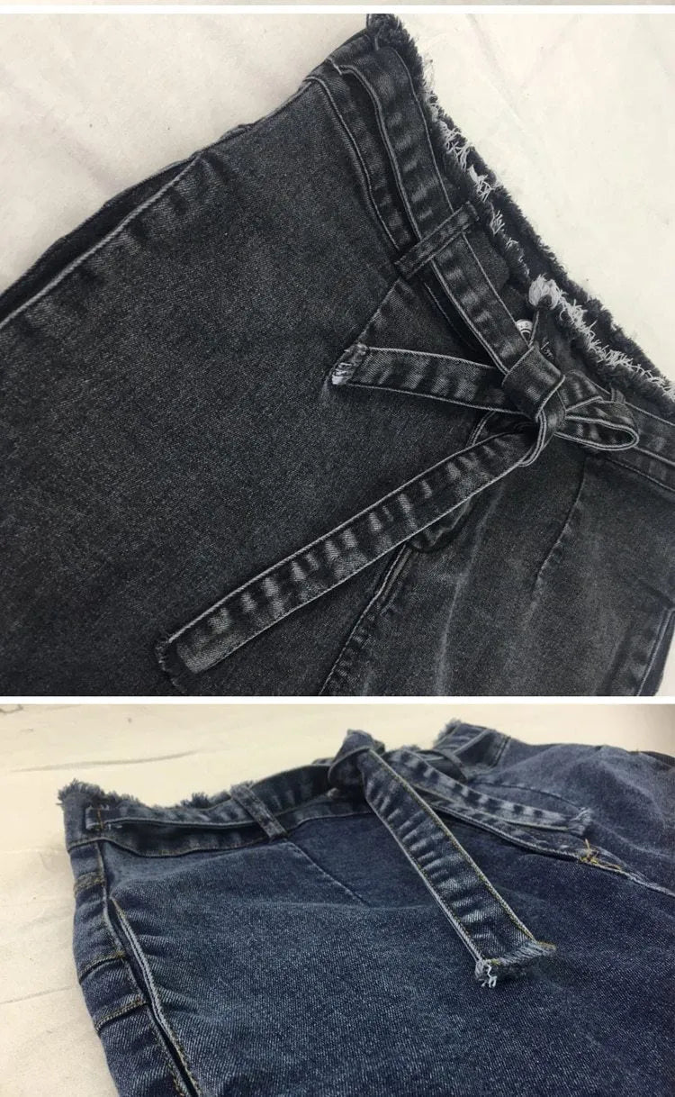 Men's dark blue jeans with frayed fringed hems laid flat on a surface.