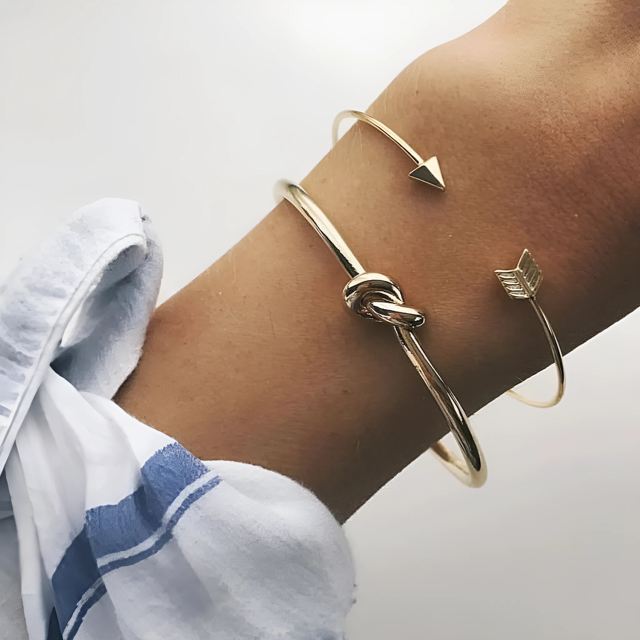 Gold electroplated alloy women's cuff bracelet with arrow and knotted design pattern