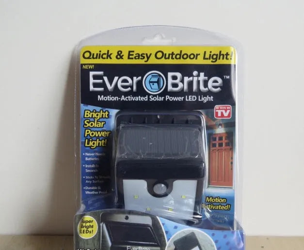 White rectangular solar-powered outdoor security light with four LED bulbs and an integrated solar panel on top.