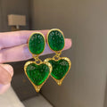 A pair of oval-shaped love heart stud earrings with a pleated surface, shown in one of four colour options.