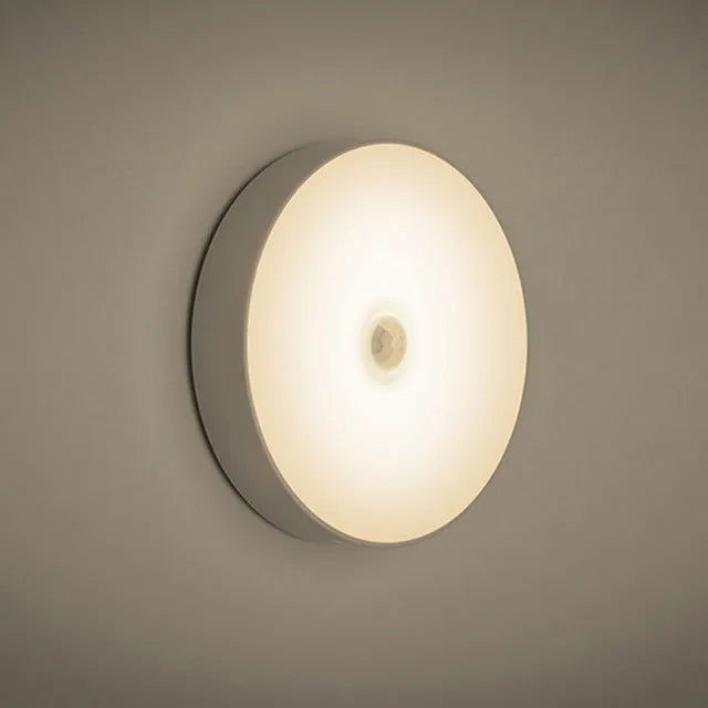 White circular motion sensing night light with USB charging port mounted on wall