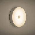 White circular motion sensing night light with USB charging port mounted on wall