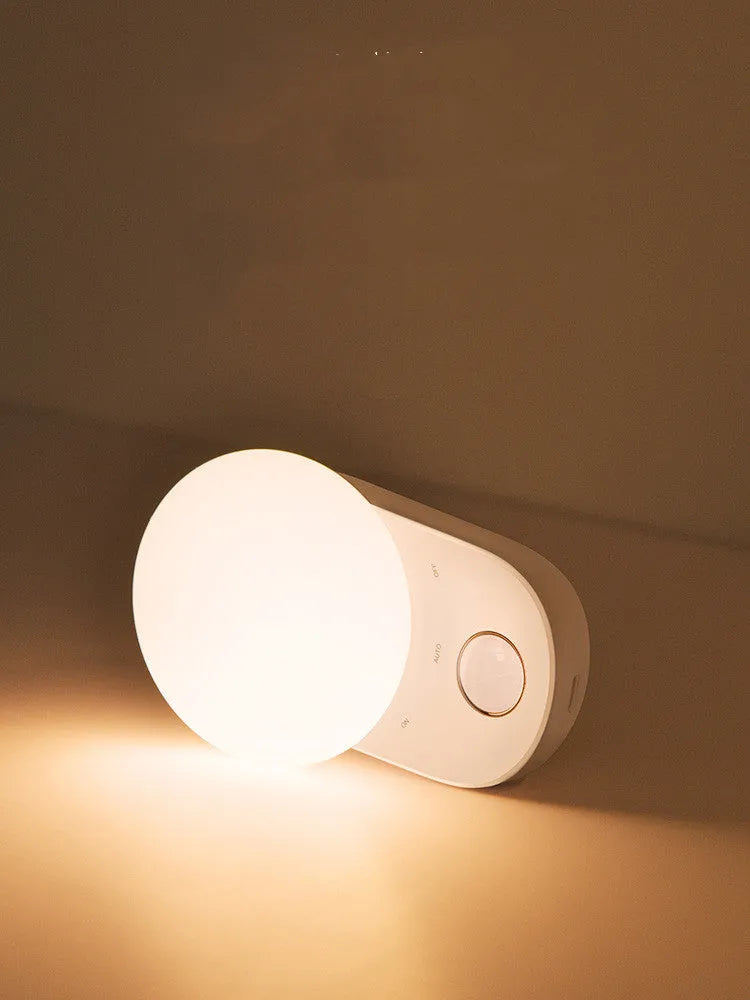 White circular rechargeable sensor night light with warm LED illumination for bedside placement