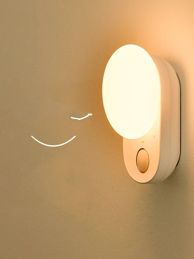 White circular rechargeable sensor night light with warm LED illumination for bedside placement