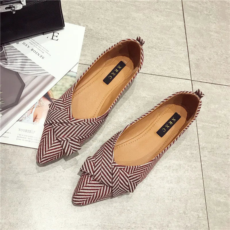 Women's black pointed toe low heel flats with a shallow mouth design on a plain background